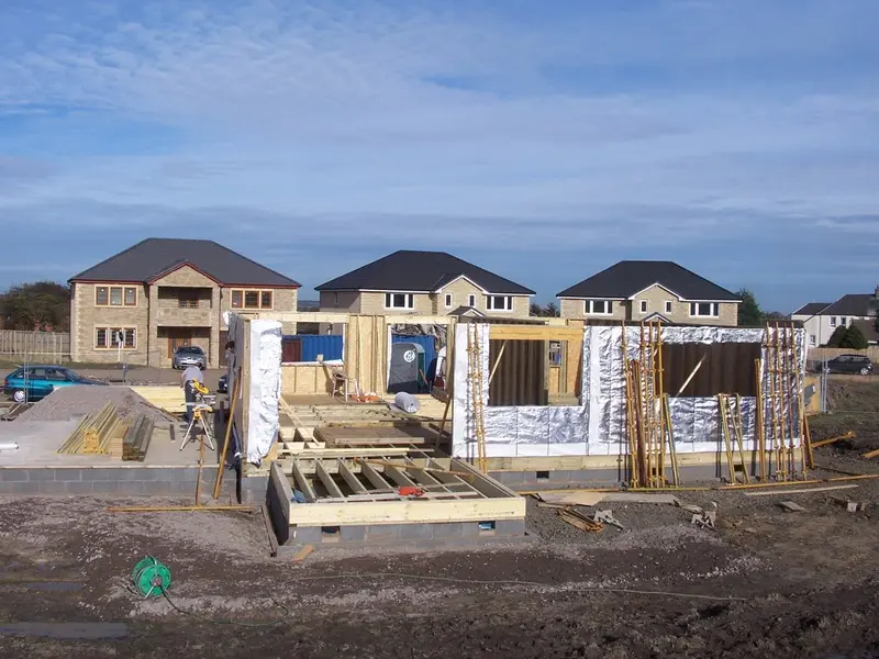 Timber frame panels going up, with finished homes on the street behind