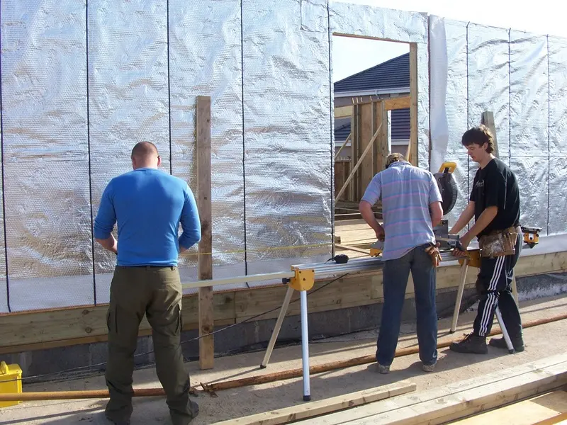 Joiners cutting timber beside the newly erected wall panels