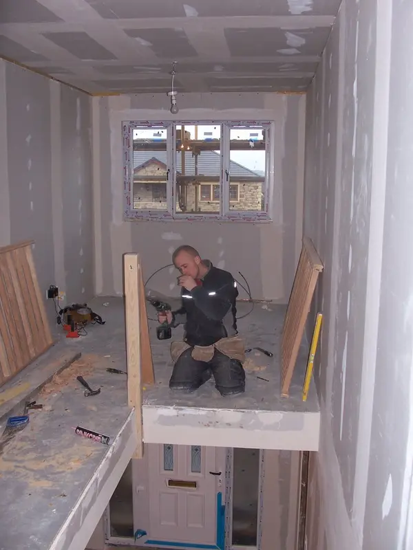 Joiner fitting the balustrade on the plasterboarded landing