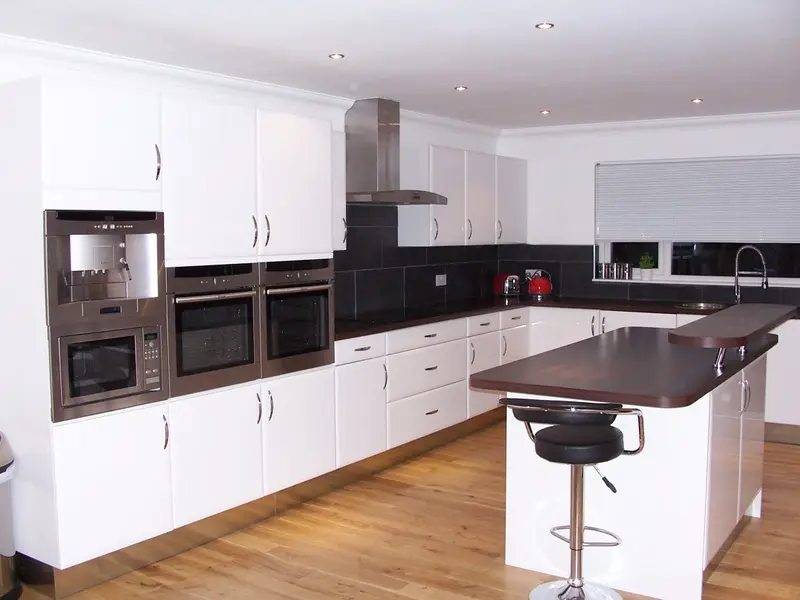 Finished kitchen with gloss white units, integrated ovens and breakfast bar