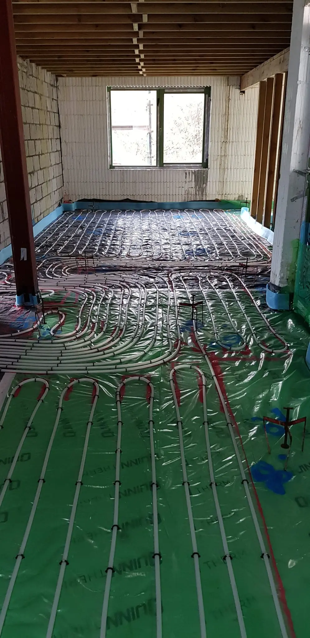 Underfloor heating pipes running the length of a room