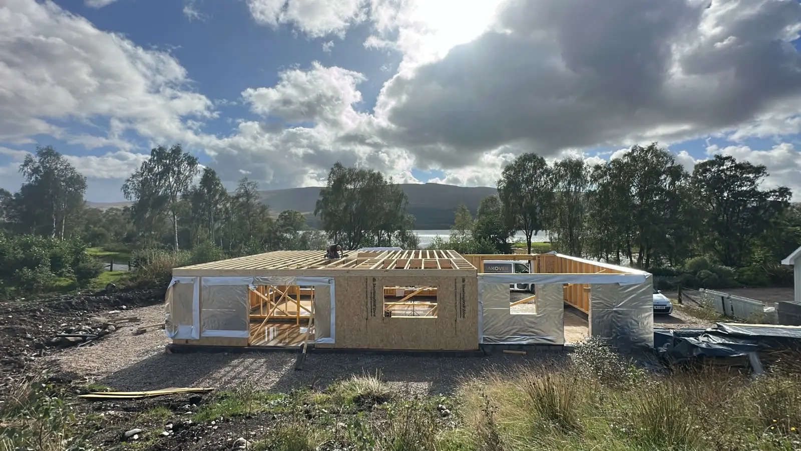 Timber frame of the founder's home rising beside the loch
