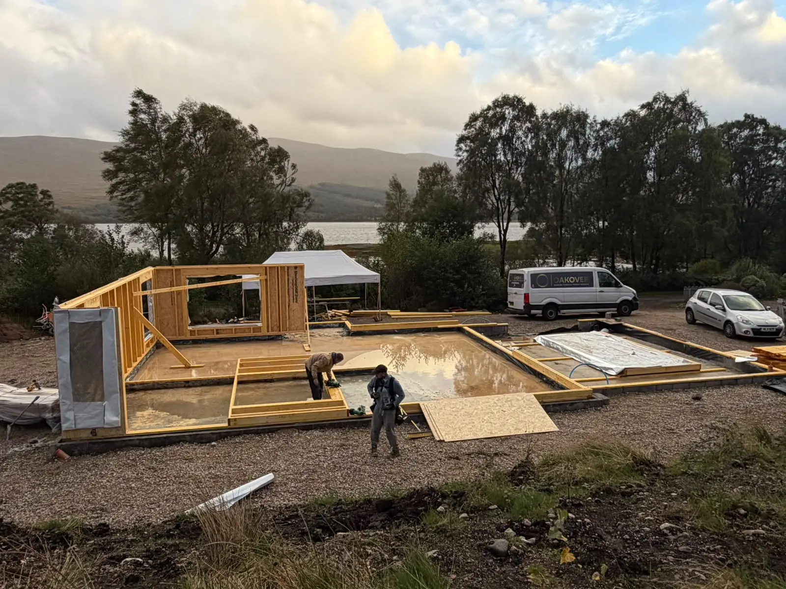 First timber frame wall panels standing on the slab beside the loch