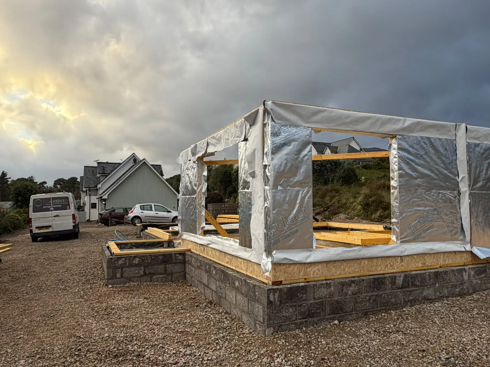 Timber frame corner wrapped in breather membrane on the blockwork base