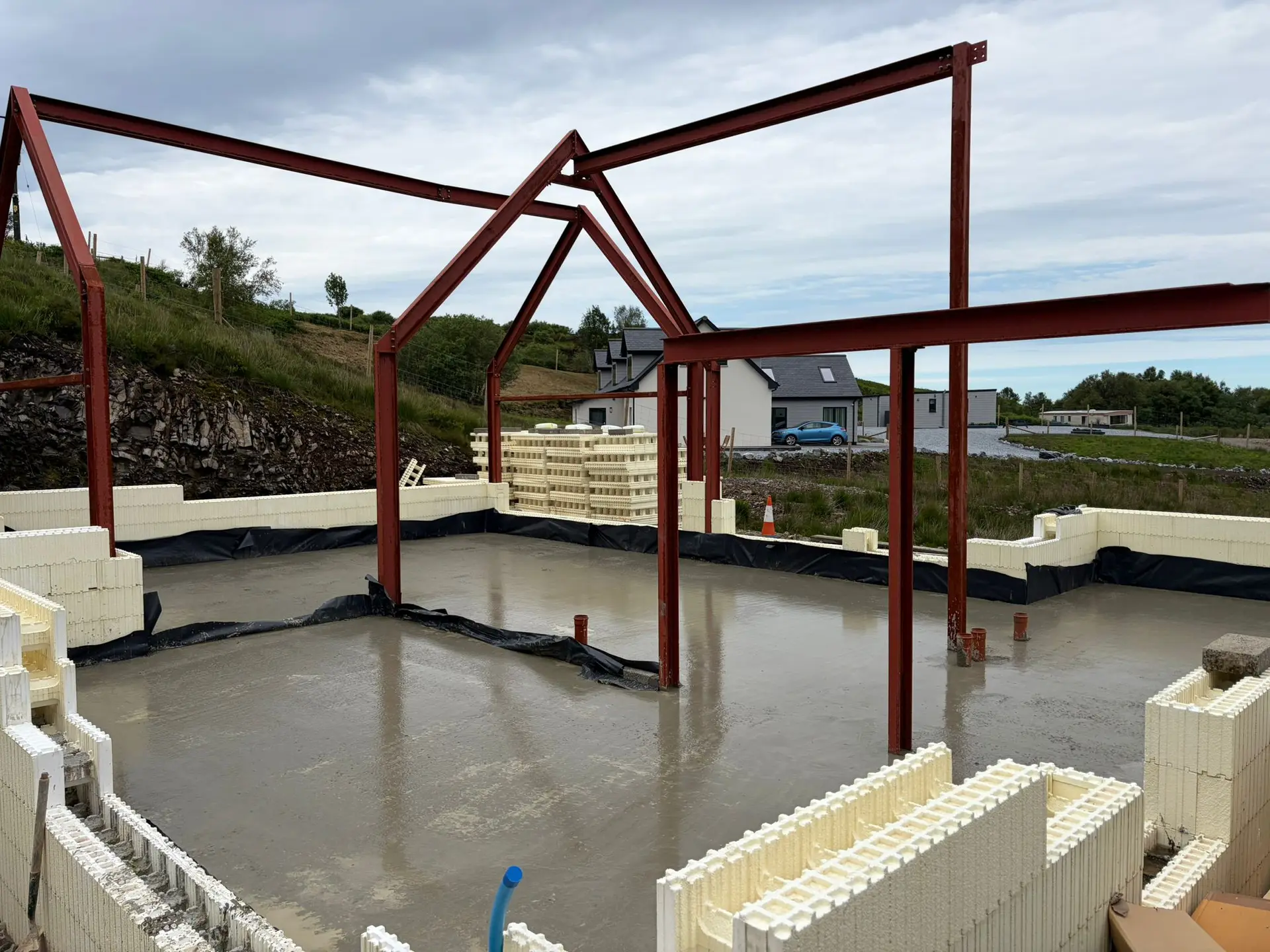 Poured slab and steel portal frames, with neighbouring homes beyond